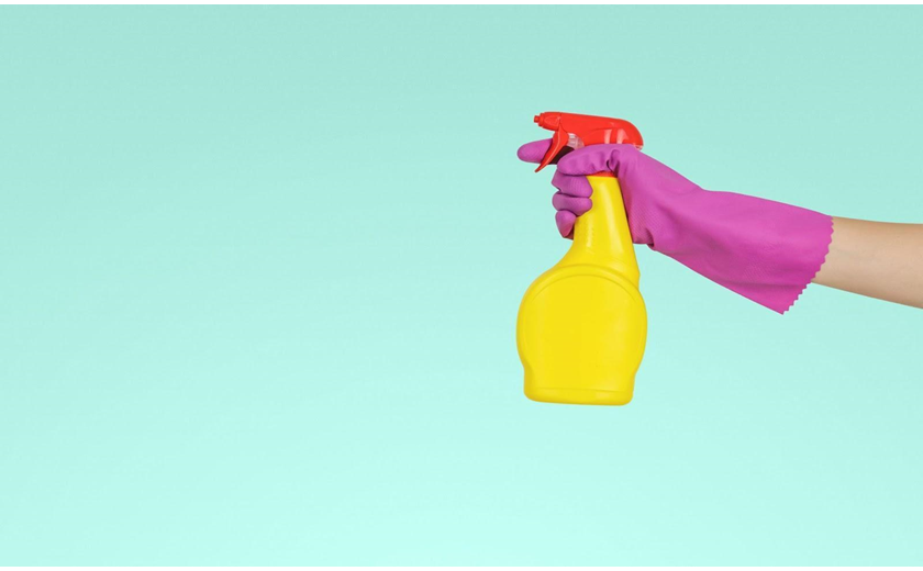 Hand wearing pink glove spraying laminate flooring cleaner